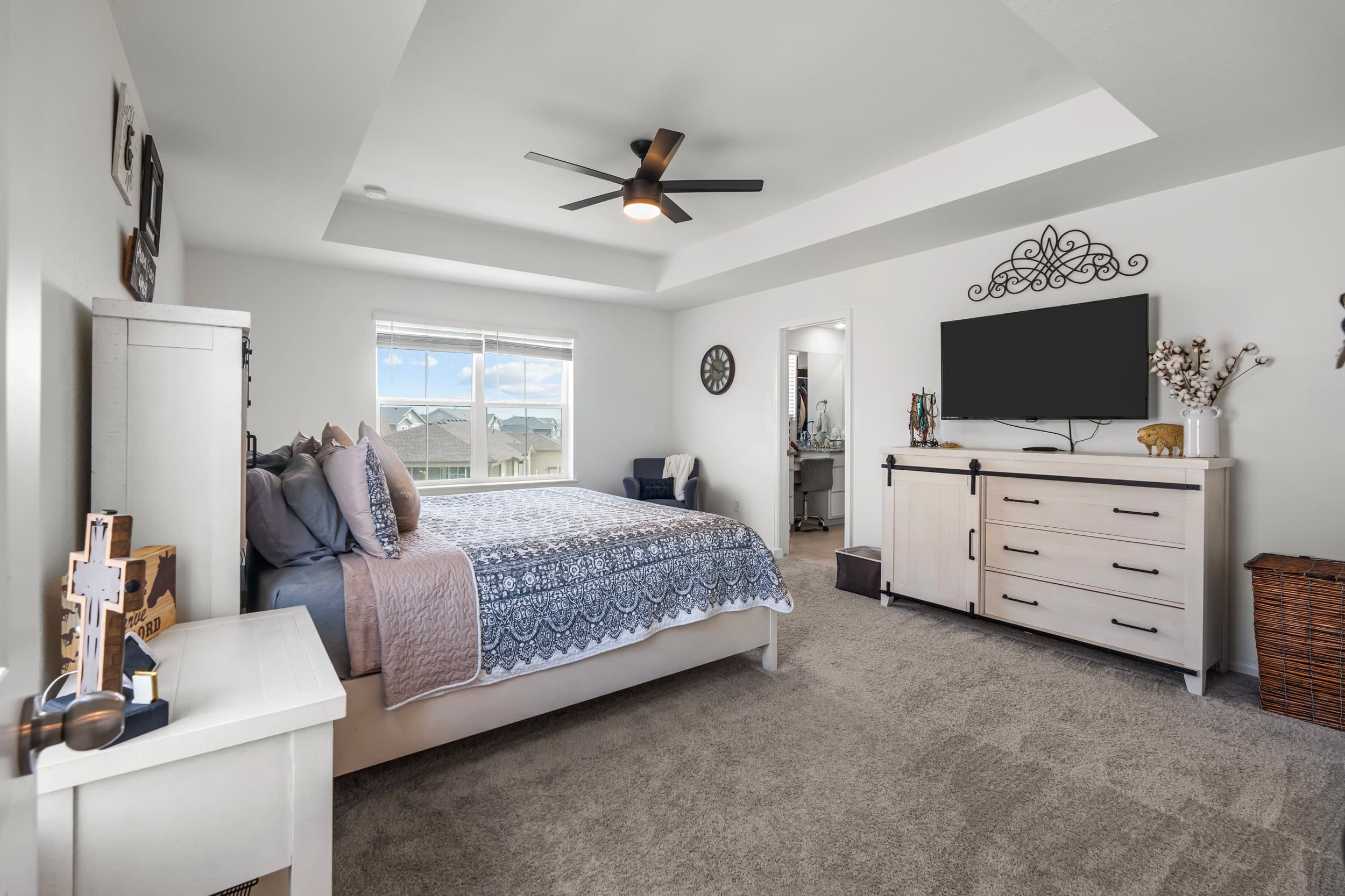 Interior bedroom with a tray ceiling and walk-in closet beyond